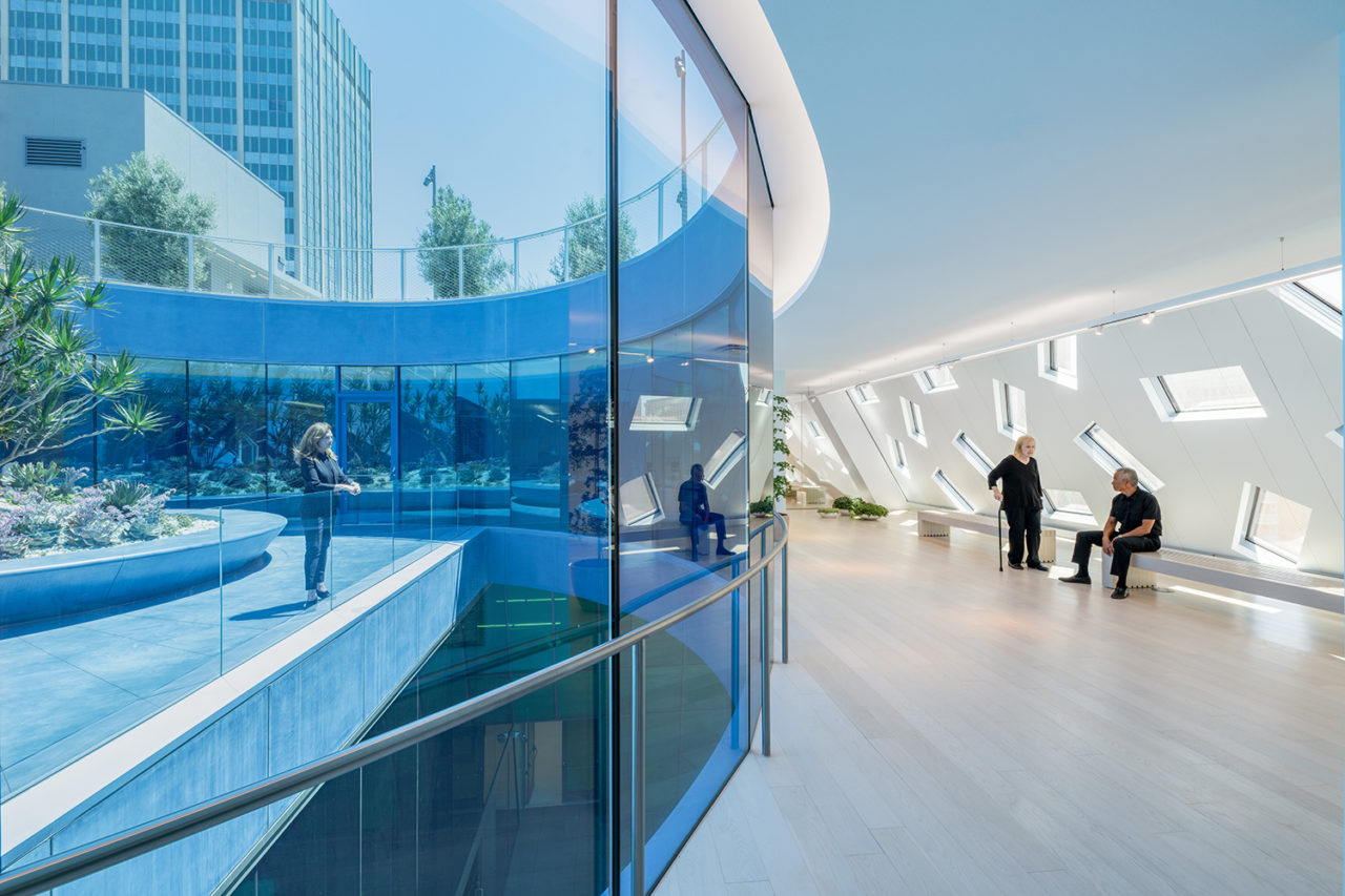 A photograph of the interior of the Audrey Irmas Pavilion, depicting white walls and a central glazed atrium.