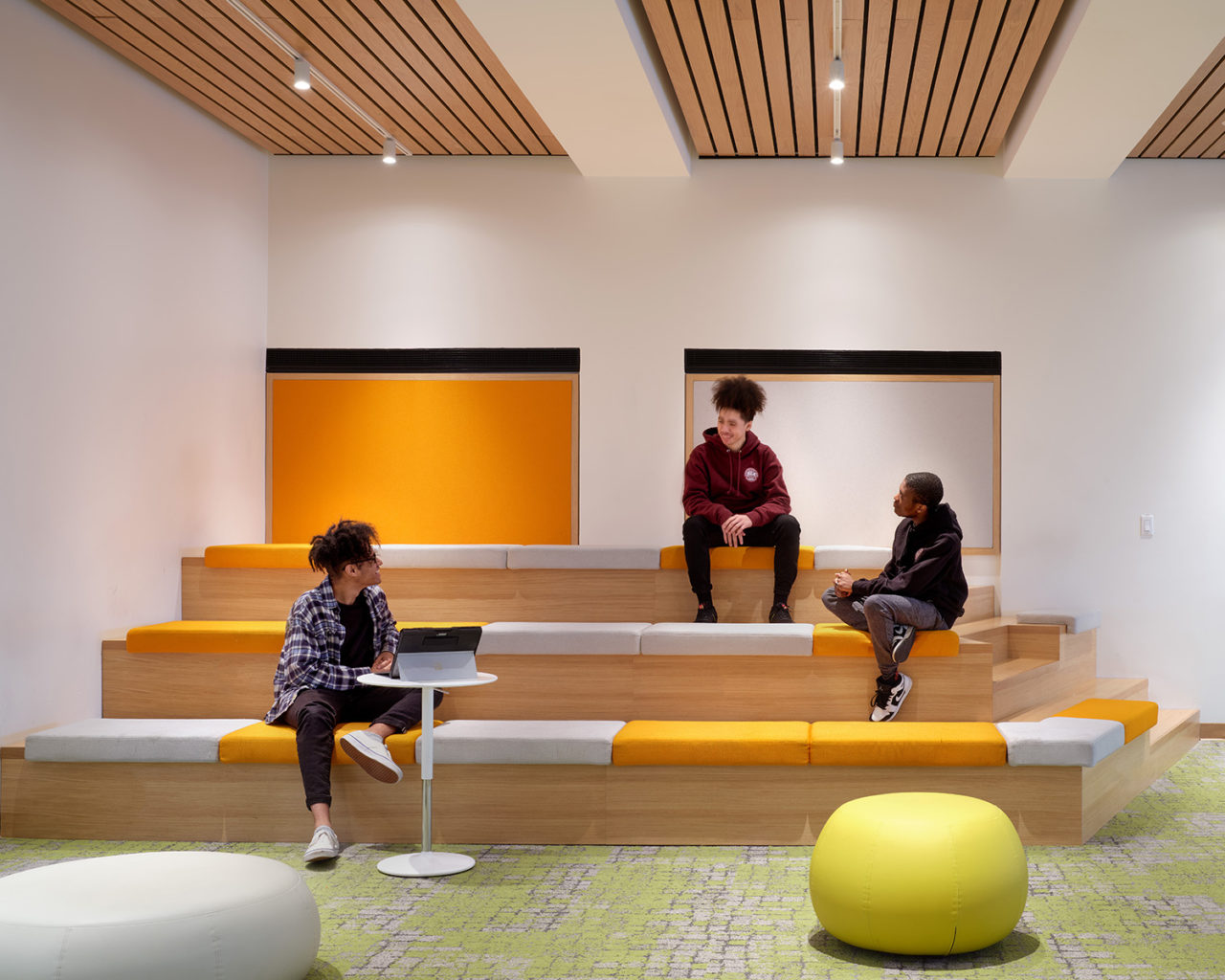 Photo of three students sitting on wooden stepped seating at the Student Union at the Manhattan School of Music.