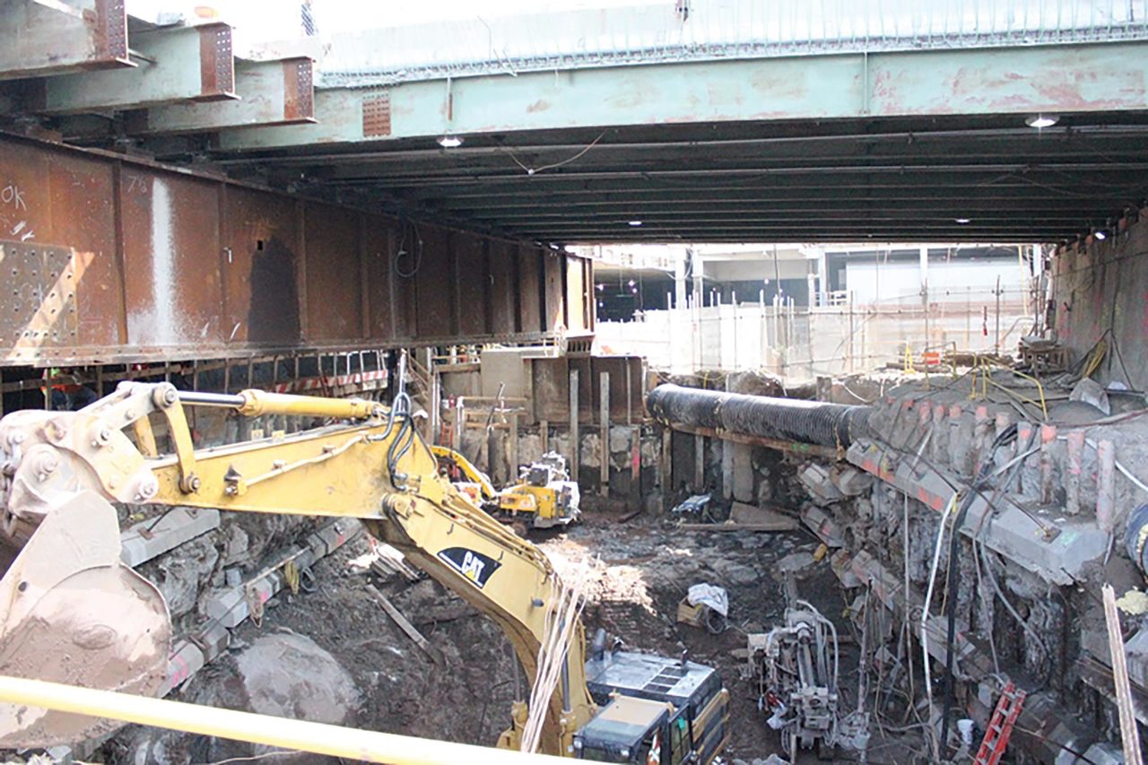 A construction site with cranes, dirt, concrete, and wires