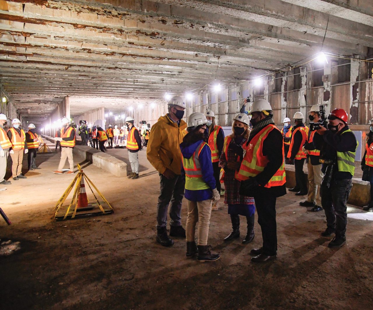 A group of people in hard hats touring a construction site underground.