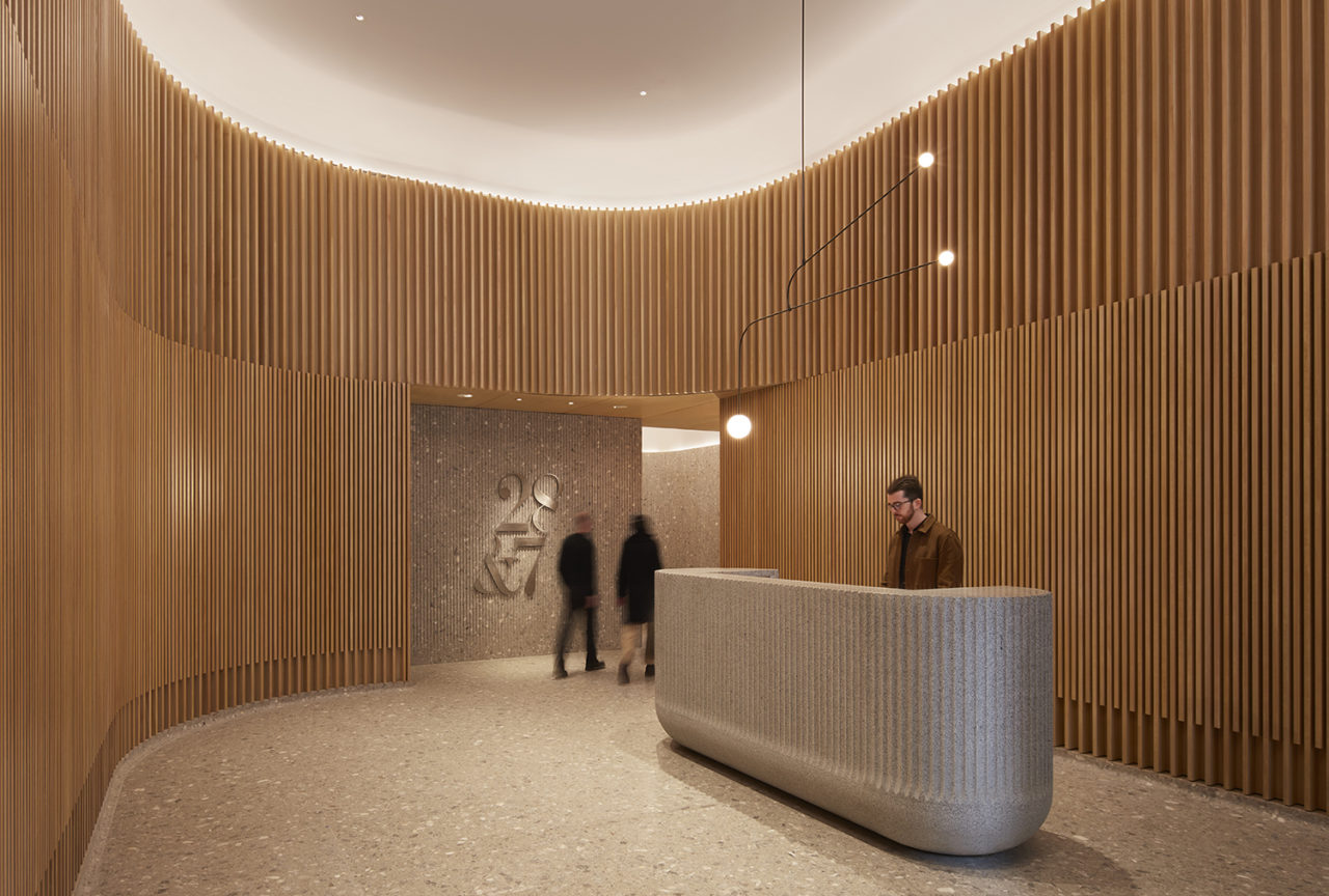 The entrance lobby of 28&7, featuring warm wood and a reception desk.