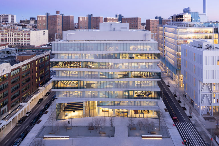 The exterior of a Columbia Business School building at dusk, highlighting the transparent nature of the facade.