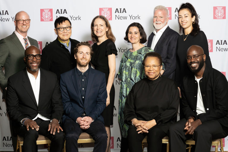 10 people arranged in front of a step-and-repeat with AIA New York logos