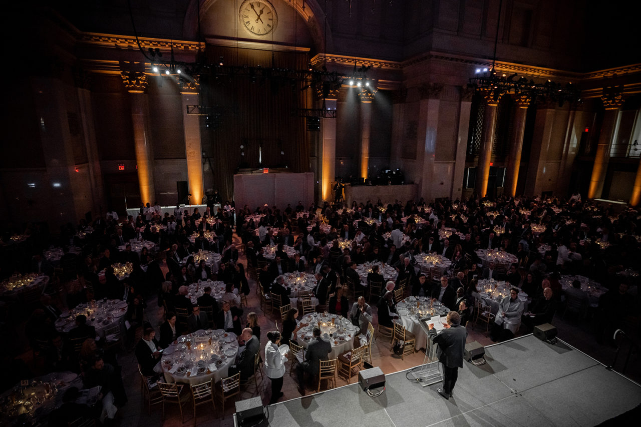 Aerial view of people sitting in a hall full of circular tables.