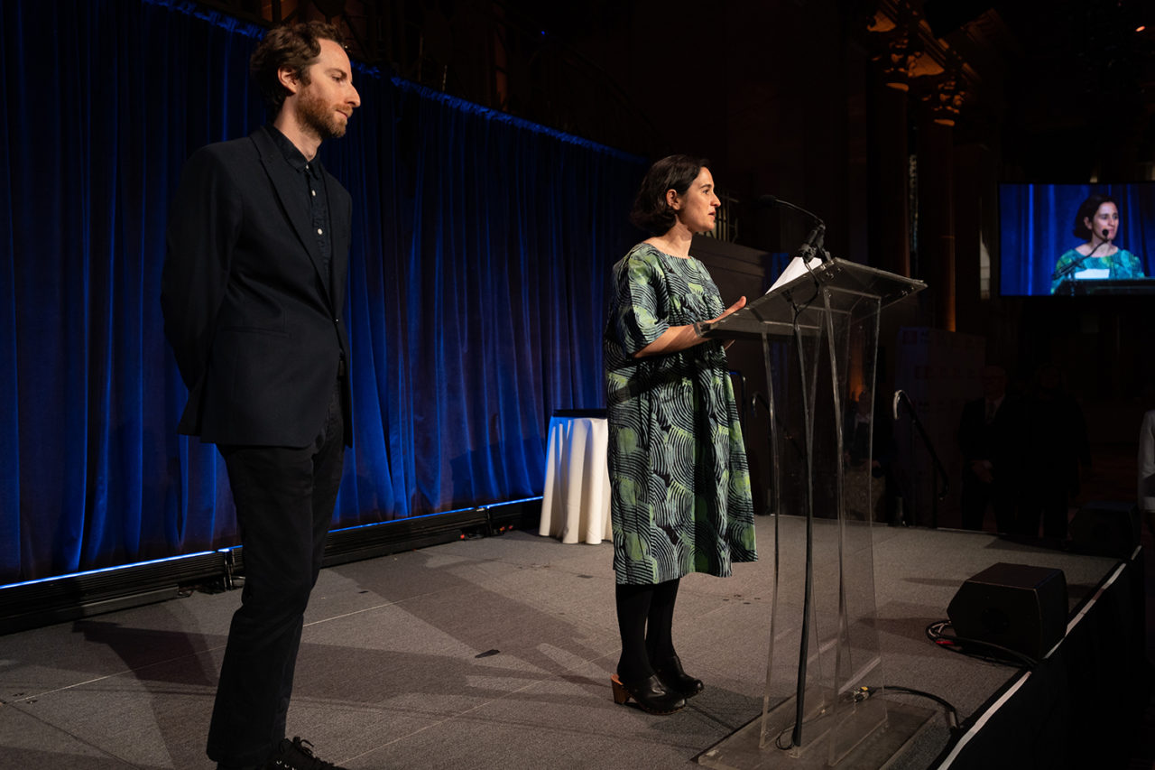 A woman stands at the podium while a man stands to her side