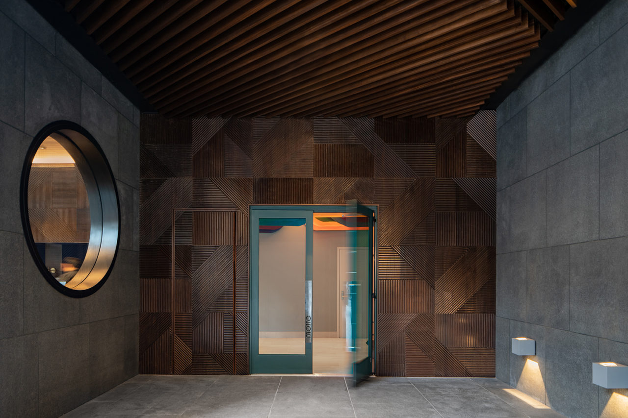 Receded entrance with a glass double door with turquoise framing.