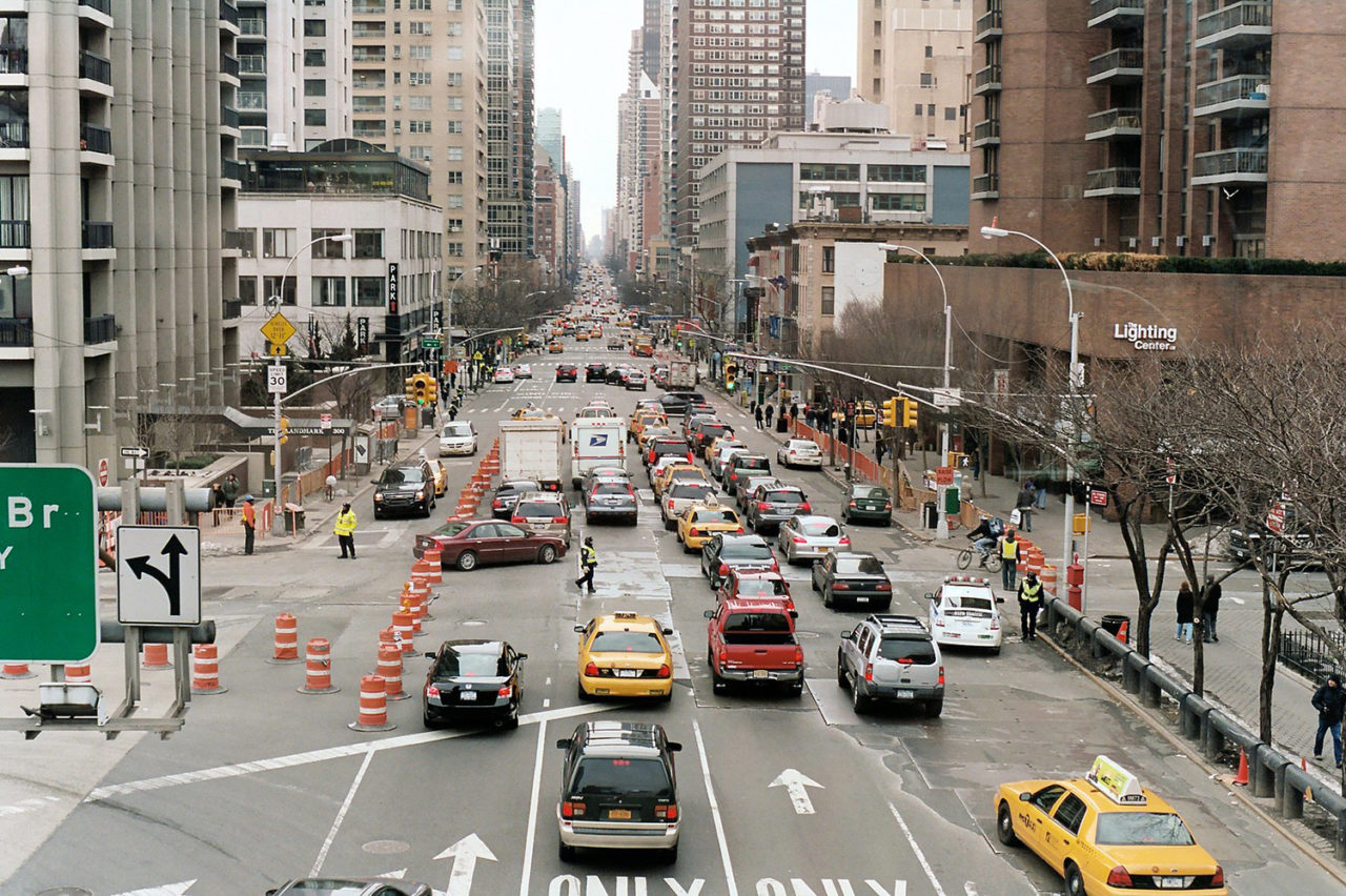 Aerial view looking down a street with many cars and tall buildings on either side