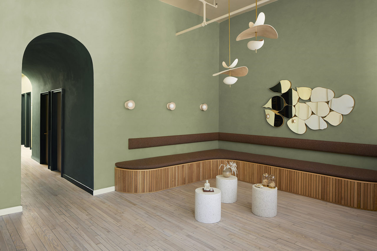 Interior with an arched doorway, sage green walls, and a wooden bench