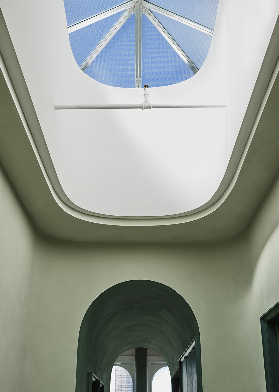 A rounded skylight provides natural light to a sage green interior