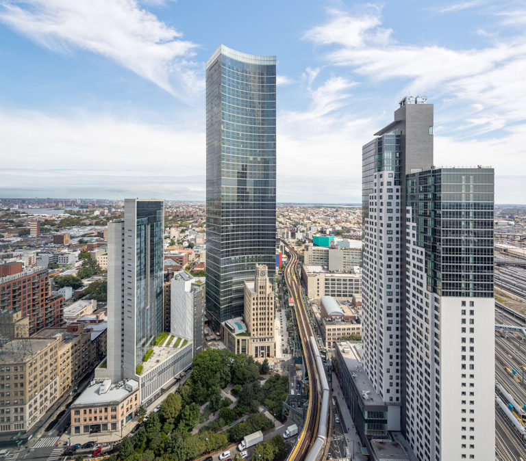 Curved glass skyscraper towers over buildings around it.