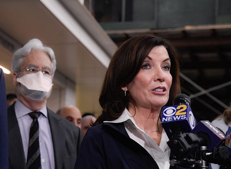 Woman speaking into a reporter's microphone.