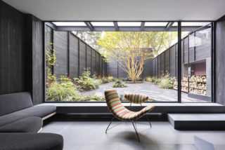 House interior with a large window looking out on an inner courtyard and a colorful chair in the foreground