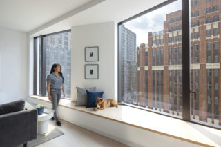 Interior of 11 Hoyt residence with a woman standing and looking out a large angled window