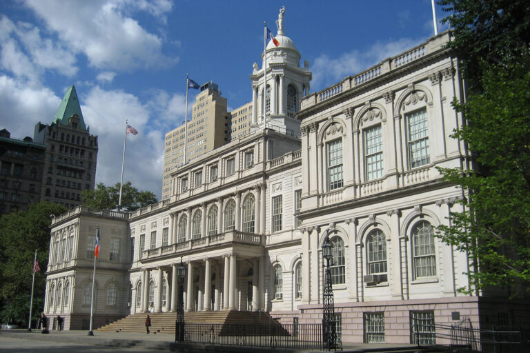 New York City Hall at ground level, featuring two-story a white building with neoclassical details.