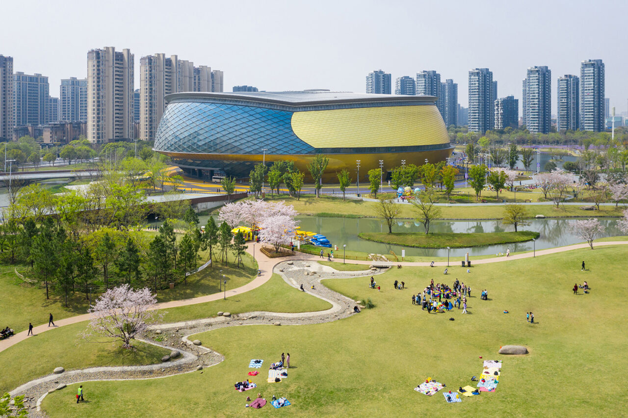 Modern-looking, bowl-shaped sports venue in the midst of a grassy landscape.