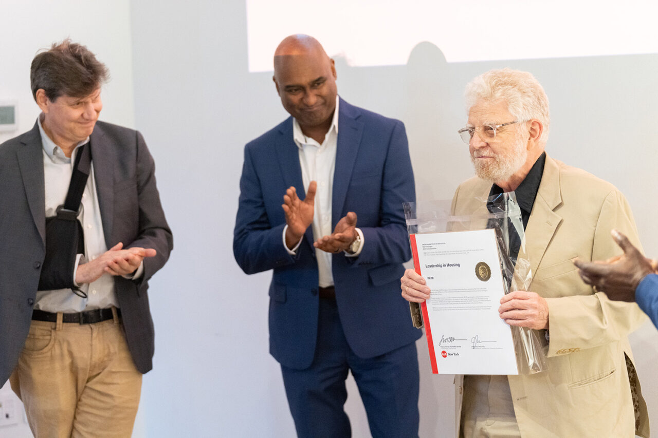 Two men applaud as one holds certificate