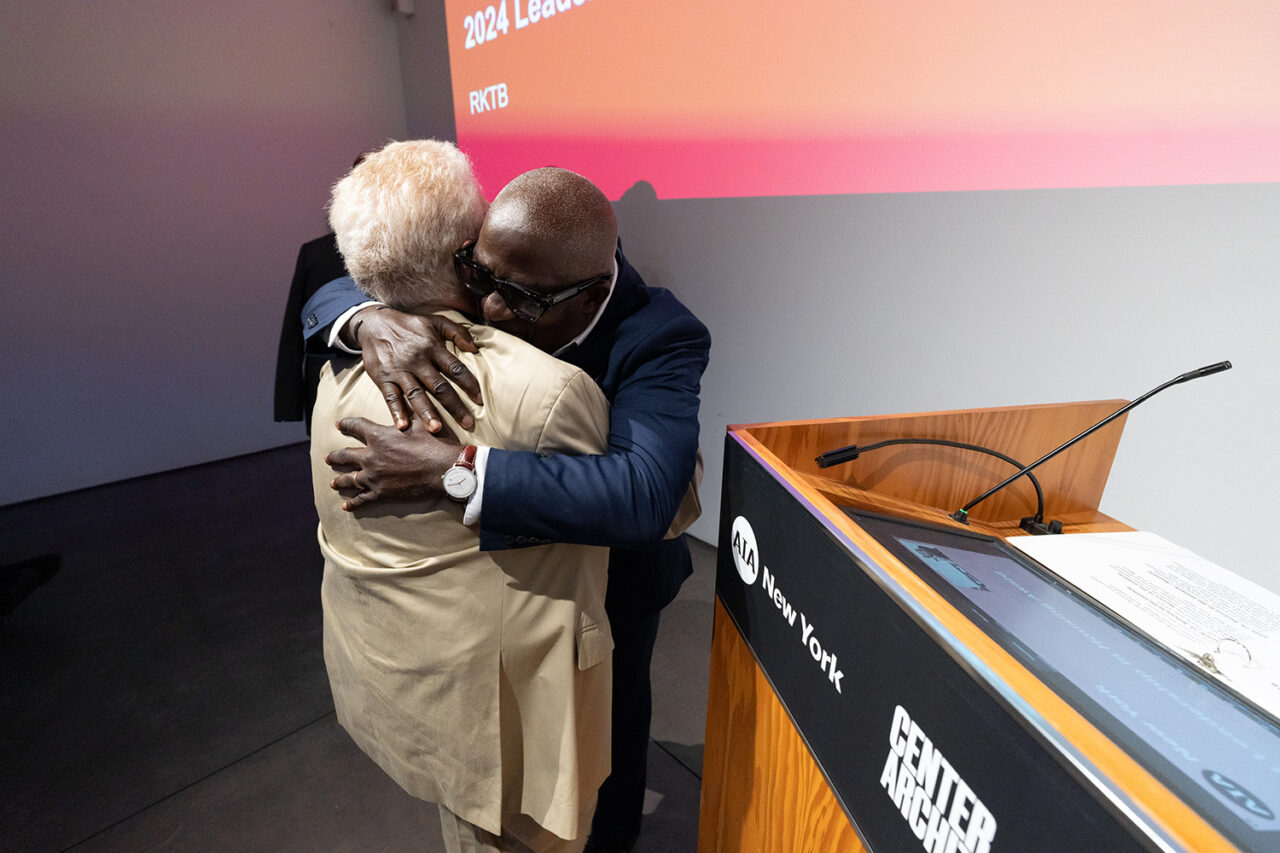 Two men grasp one another in an embrace by the podium