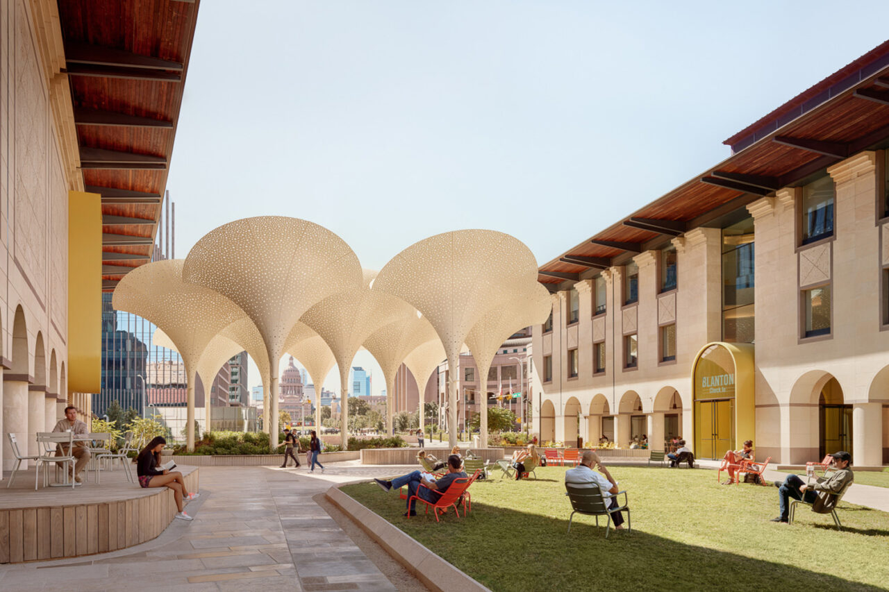 A landscape view of people relaxing on the lawn by the Blanton Museum of Art.
