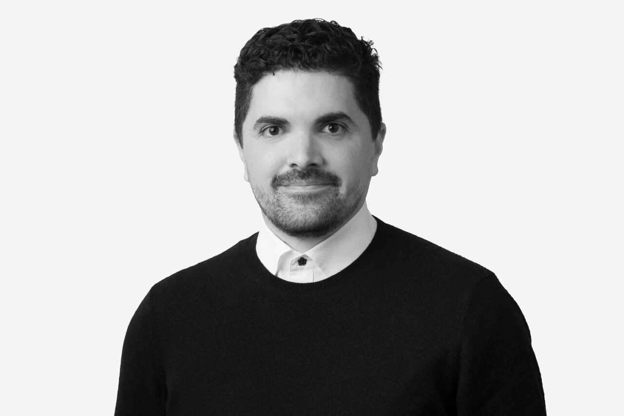 Black and white headshot of a light-skinned, dark haired man.