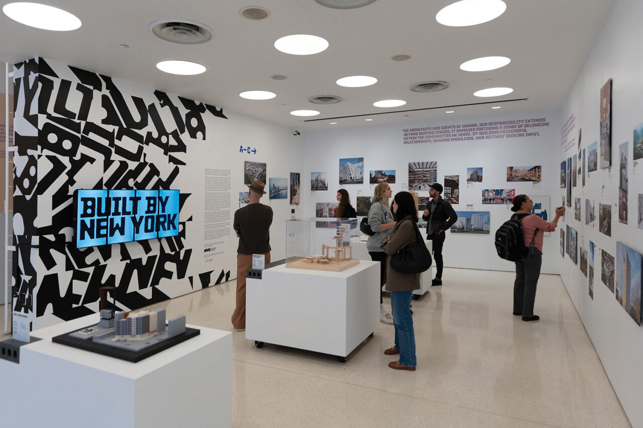 Interior of the ground floor Center for Architecture gallery space. People are viewing photos on the walls.