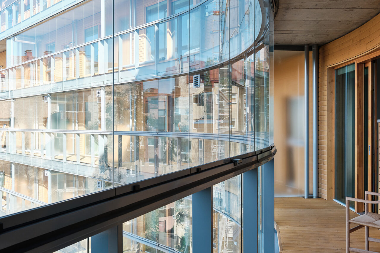 A view of the glass facade and balcony of the apartment building.