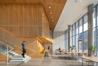 A staircase on the left leads out onto a central meeting area with tables.