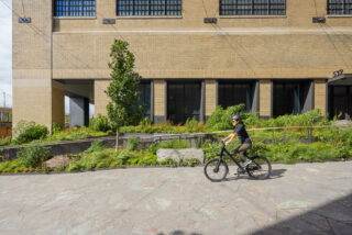 A person rides their bike down the sidewalk by St. John's Terminal.