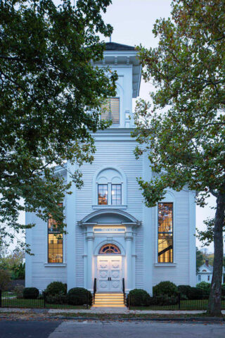 Exterior white church structure with trees on either side.