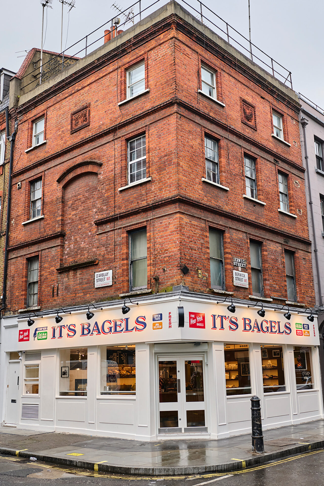 Exterior of bagel shop. Red brick top three floors and white storefront on the ground floor.