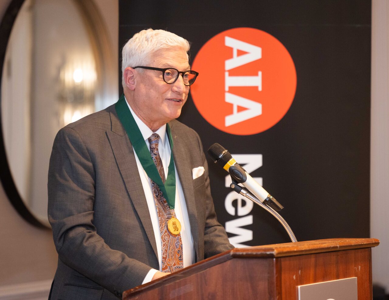 Geier stands at the podium with the AIA New York State logo in the background.