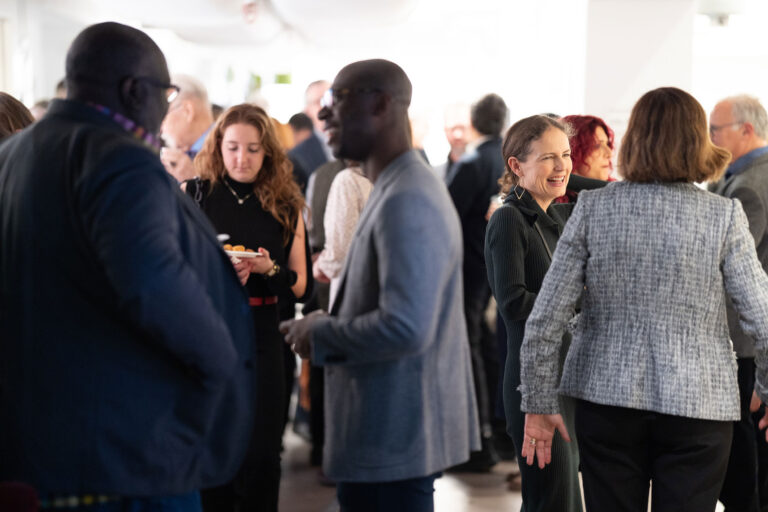 A crowded room of people talking with each other