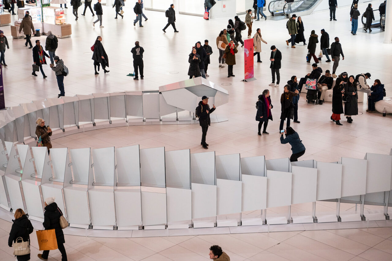 Close-up of a white winding snake sculpture with people milling around it.
