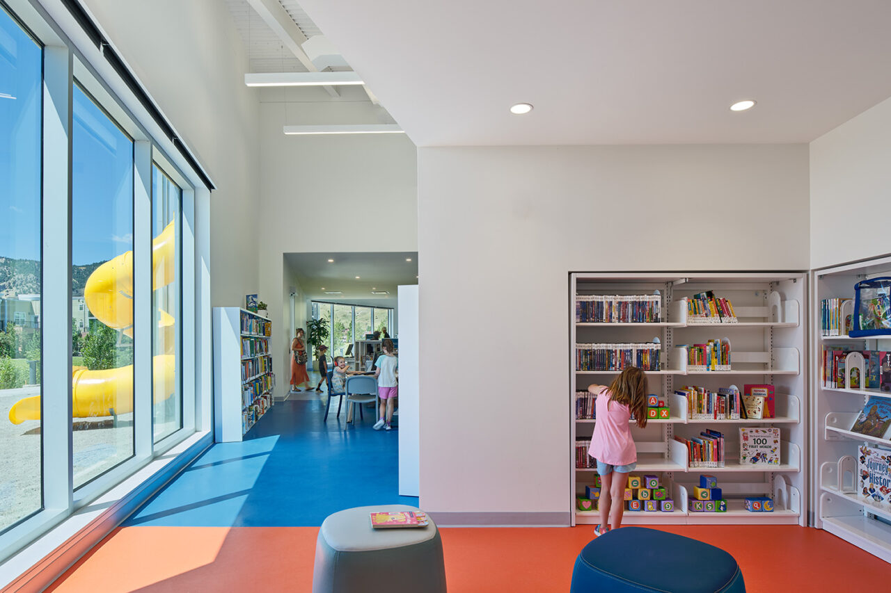 Interior shot of library. The back of a girl in front of a bookshelf.