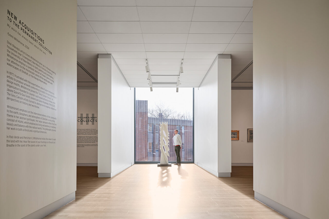 Interior of museum, showing a man next to a sculpture by a window.