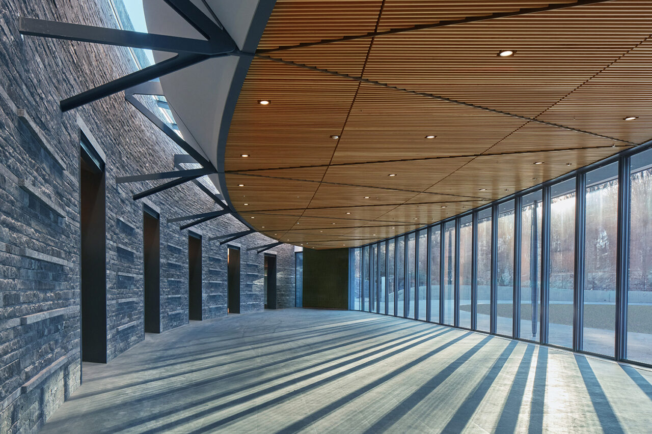 Interior of spacious walkway with floor-to-ceiling windows.