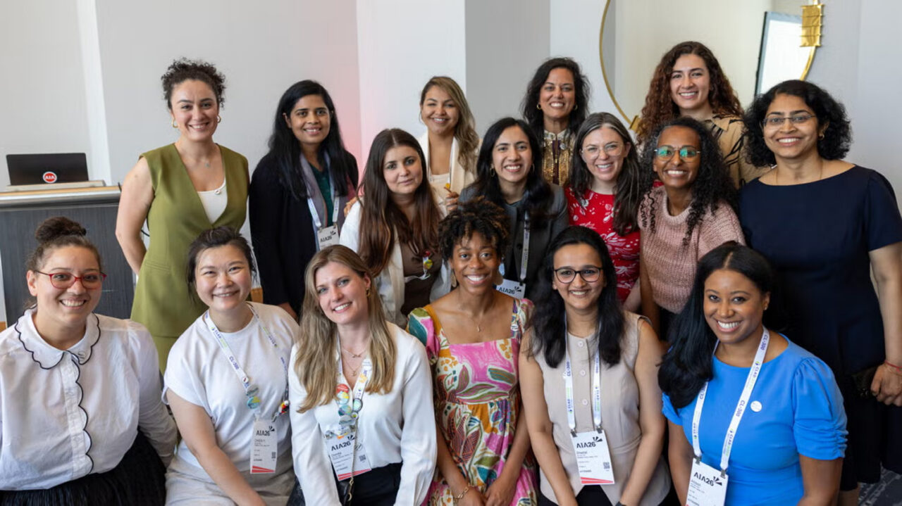 A group of 16 racially and ethnically diverse women posing and smiling for the camera