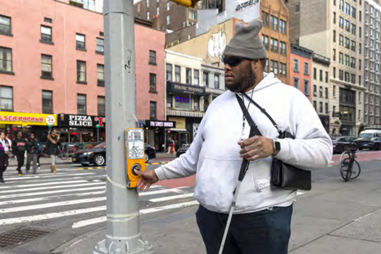 A man with a cane waiting to cross the street