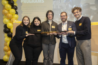 The winning team, RAMSA, holding their trophy in the form of a giant pencil.
